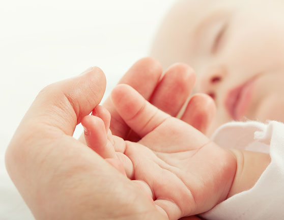 Mano de un bebé sobre una mano adulta