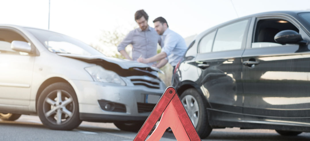 Dos personas rellenando un parte de accidentes tras un choque de coche